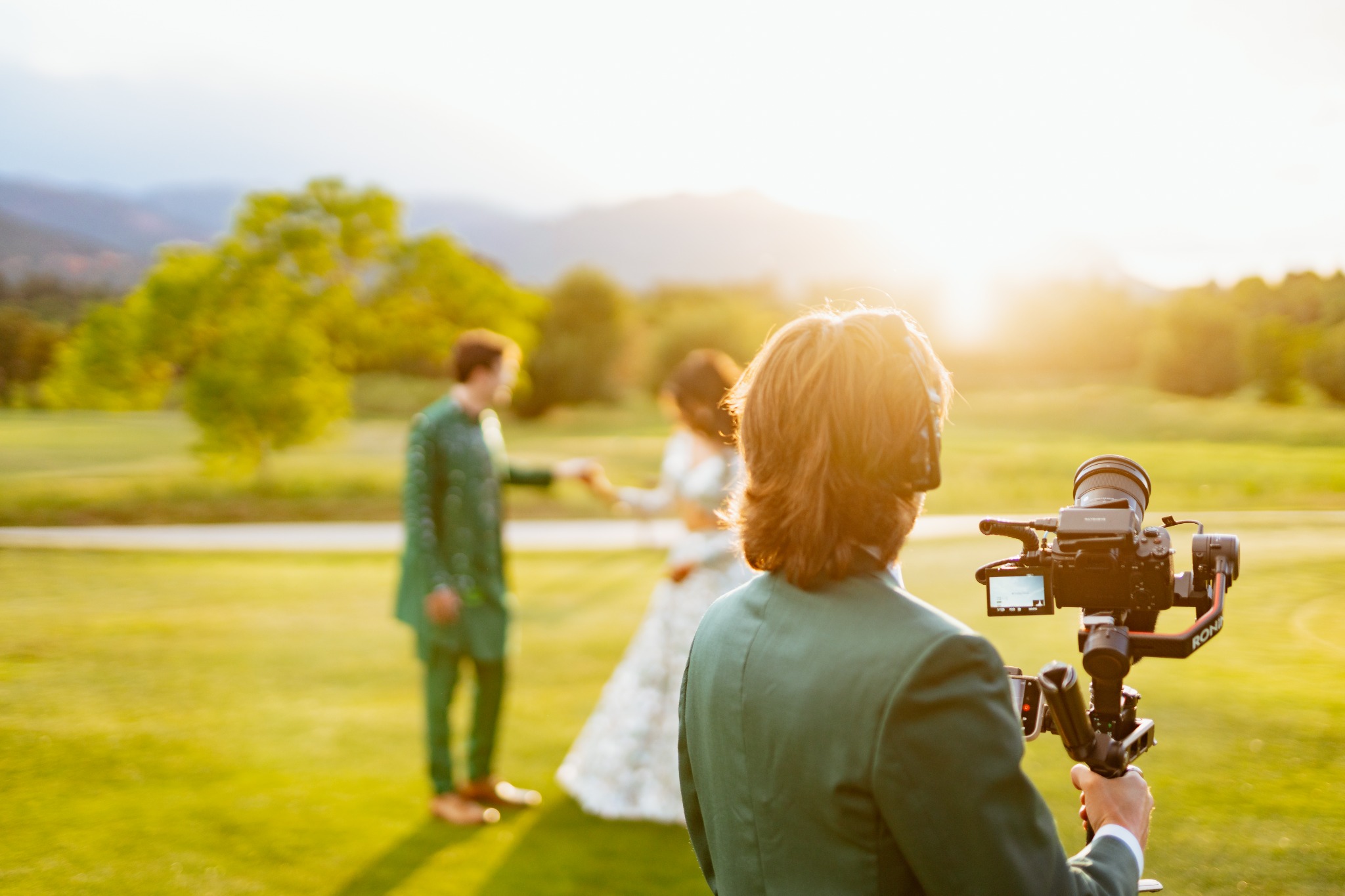 Videographer filming a wedding couple with a gimbal at sunset