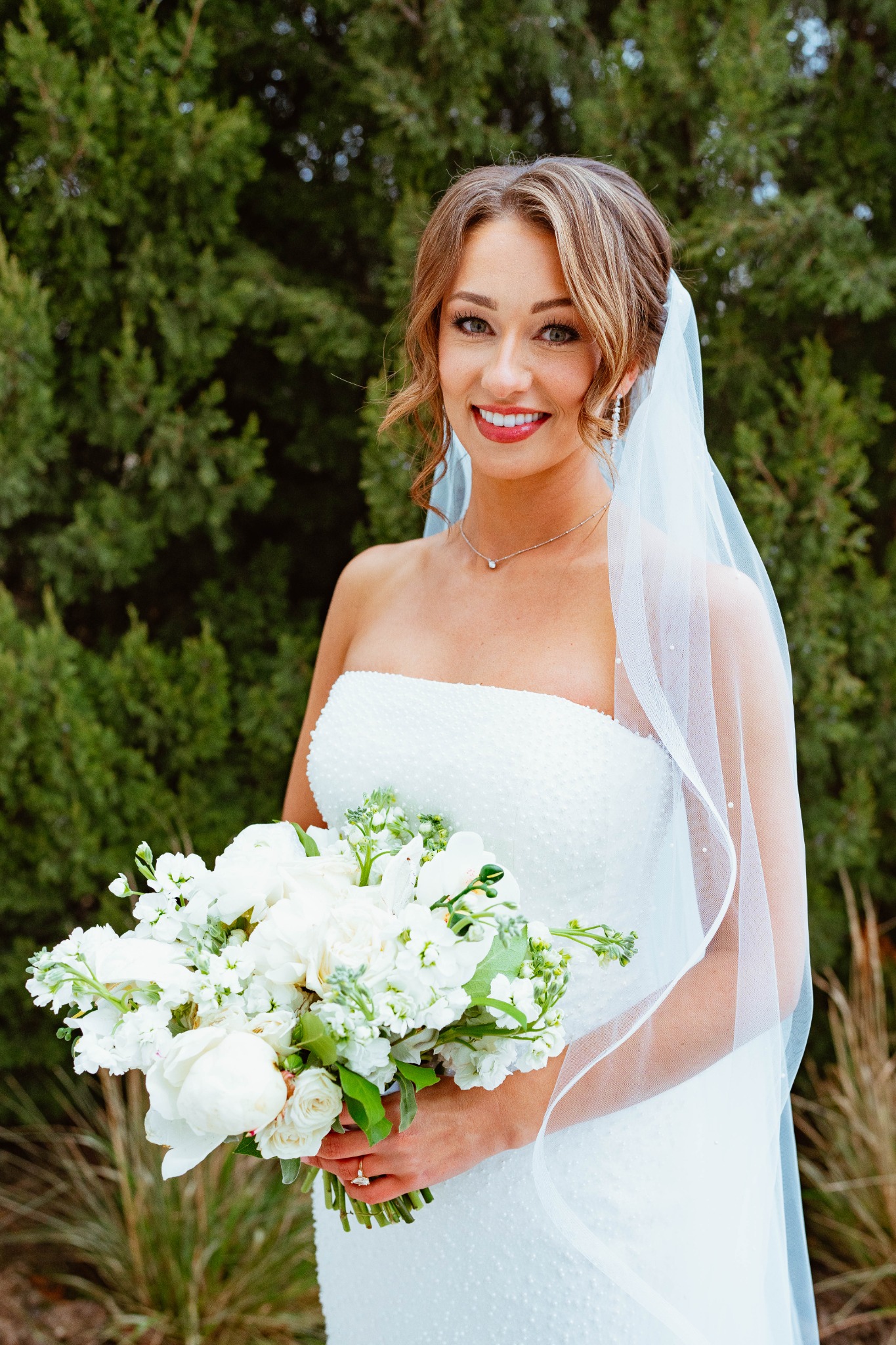 Bride holding a white bouquet outdoors